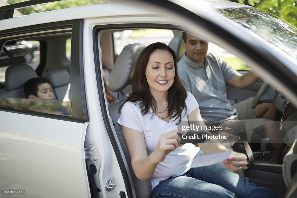 Women Using Smart Phone To Deposit Check In Car