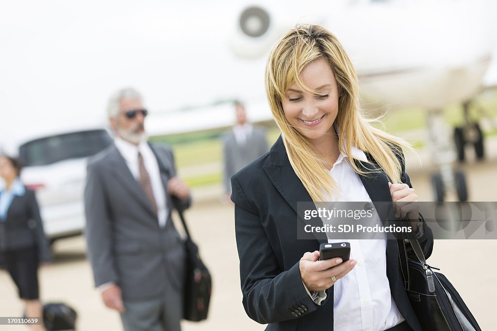 Business woman checking cell phone and smiling.