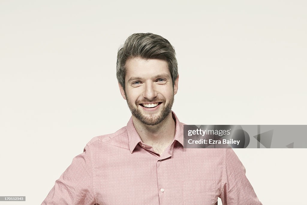 Man in a pink shirt smiling.