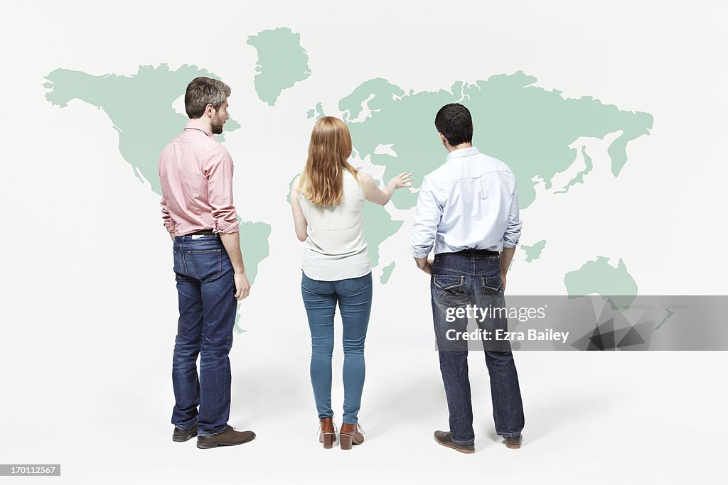Group of people chatting in font of world map.