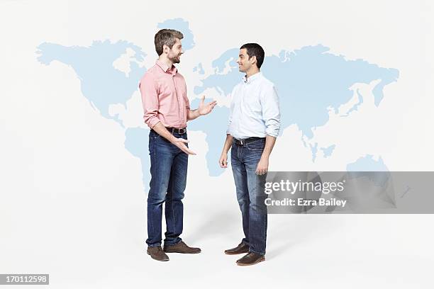 two men chatting in front of world map. - two people standing stock pictures, royalty-free photos & images