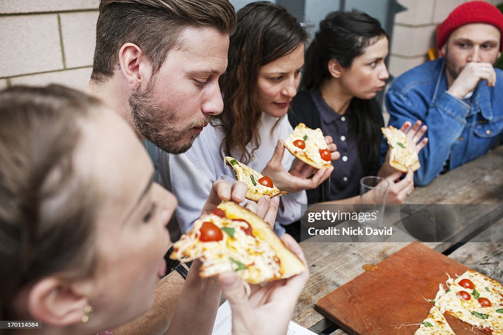 Group of friends hanging together out eating pizza at a restaurant