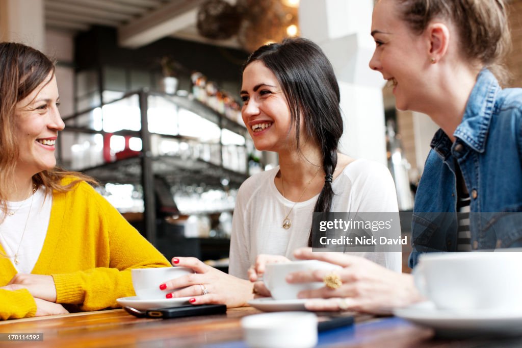 Female friends laughing together at a trendy cafe