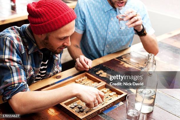 two young men playing backgammon at local cafe - game night leisure activity foto e immagini stock