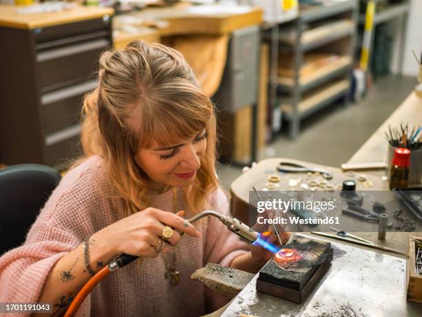 smiling craftsperson welding gold ring at workshop - juwelier stockfoto's en -beelden