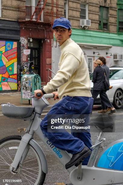 Joe Jonas rides a bicycle in the rain on September 25, 2023 in New York City.