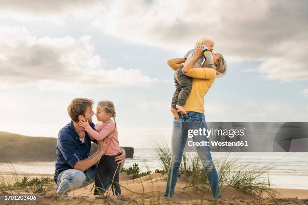 happy family embracing each other at beach - kiss sisters foto e immagini stock