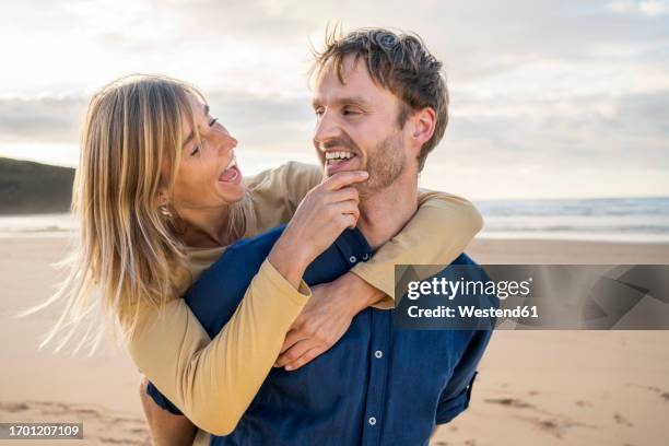 cheerful woman enjoying with man at beach - mid adult couple stock pictures, royalty-free photos & images