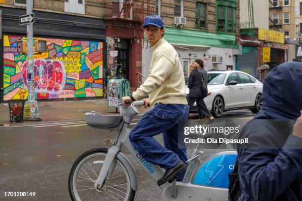 Joe Jonas rides a bicycle in the rain on September 25, 2023 in New York City.