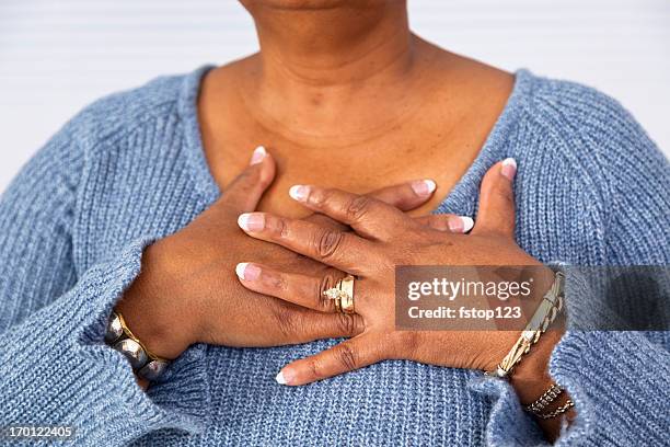 senior d'origine africaine femme dans la douleur pochettes de la poitrine - mains jointes photos et images de collection