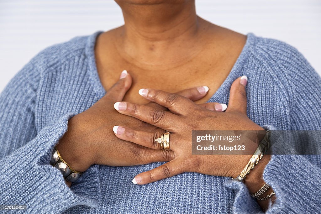 Senior African descent woman clutches chest in pain