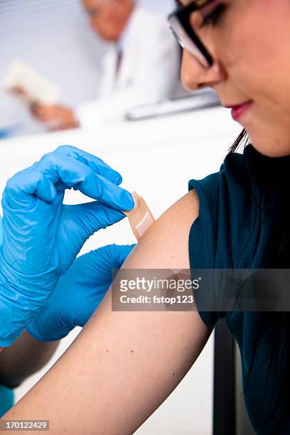 medical:  nurse at pharmacy clinic putting bandaid on injection site - applying bandaid stock pictures, royalty-free photos & images