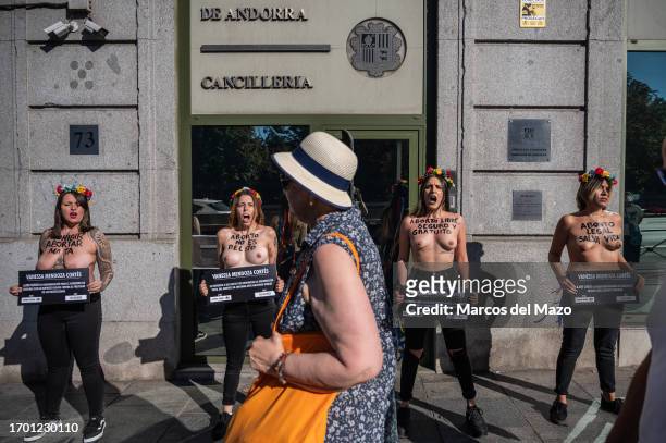 Woman walks past activists of feminist group FEMEN with their bare chests painted with messages demanding the right of abortion, protesting in front...