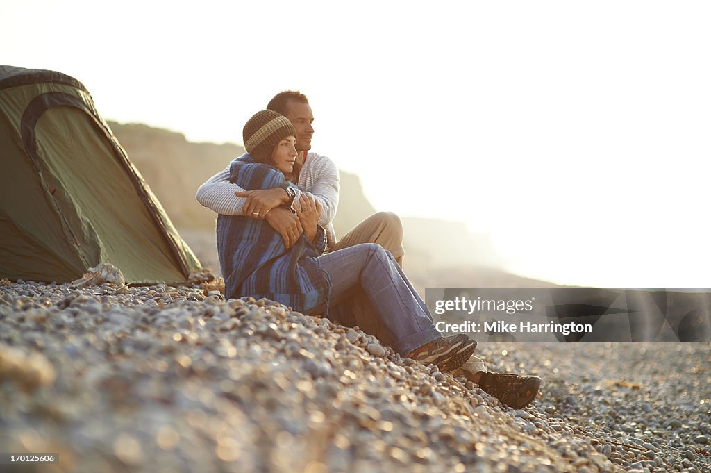 Couple embracing outside tent on beach.