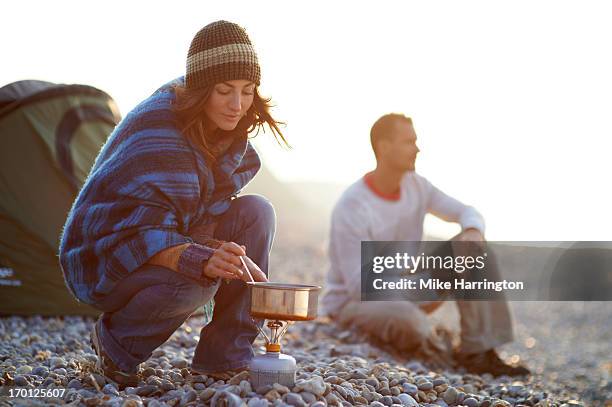 woman cooking outside tent on beach. - gas stove cooking stock pictures, royalty-free photos & images