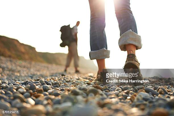 woman's shoes as she walks along pebble beach. - leg stock pictures, royalty-free photos & images