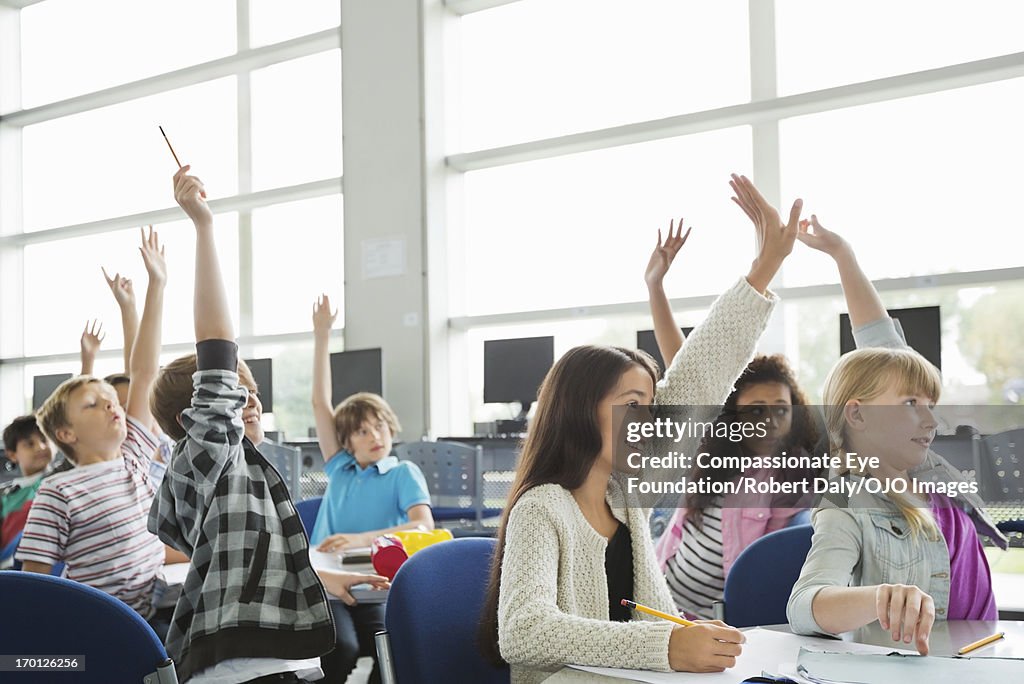 Students with hands raised in classroom