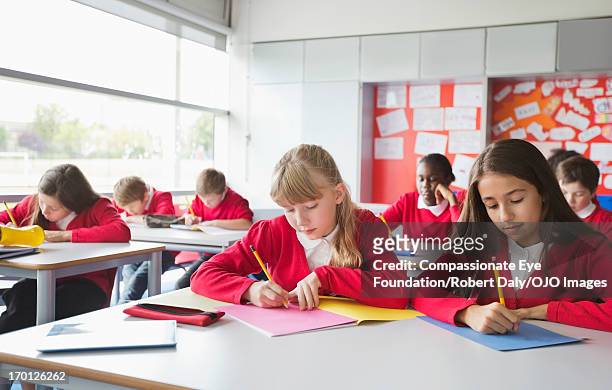 students writing in classroom - school uniforms stock-fotos und bilder