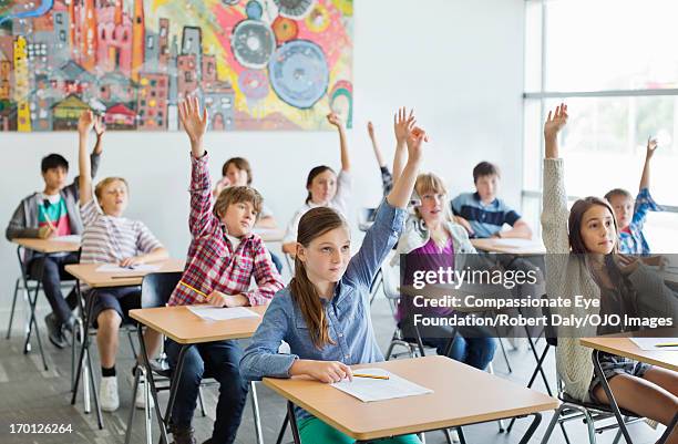 students with arms raised in classroom - englisch unterricht stock-fotos und bilder