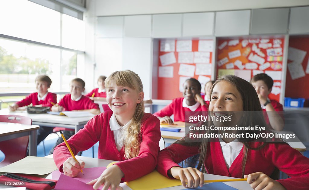 Smiling students writing in classroom