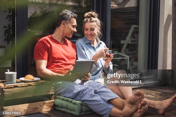 couple relaxing on balcony with digital tablet - couple balcony stock-fotos und bilder