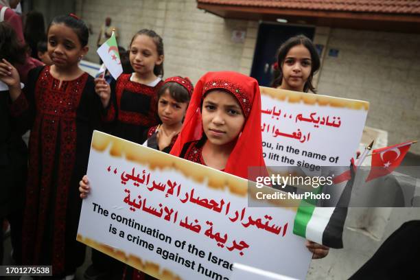 Palestinian children hold placards during a rally in front of the UNDP headquarters in Gaza City, calling for the lift of the Israeli-imposed siege...