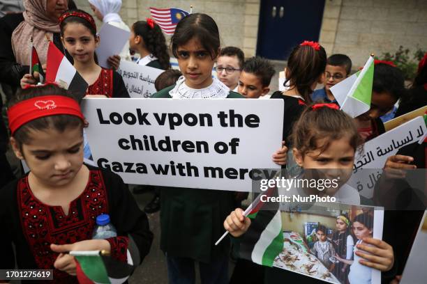 Palestinian children hold placards during a rally in front of the UNDP headquarters in Gaza City, calling for the lift of the Israeli-imposed siege...