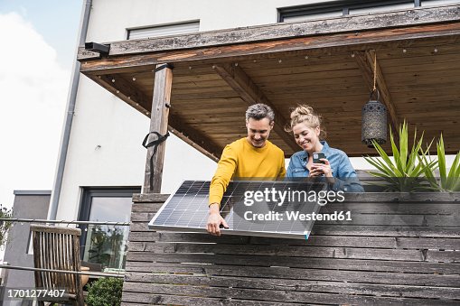 Couple installing solar panel on wooden balcony Couple installing solar panel on wooden balcony