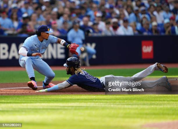 Raimel Tapia of the Tampa Bay Rays slides into third base safely against Santiago Espinal of the Toronto Blue Jays during the second inning in their...