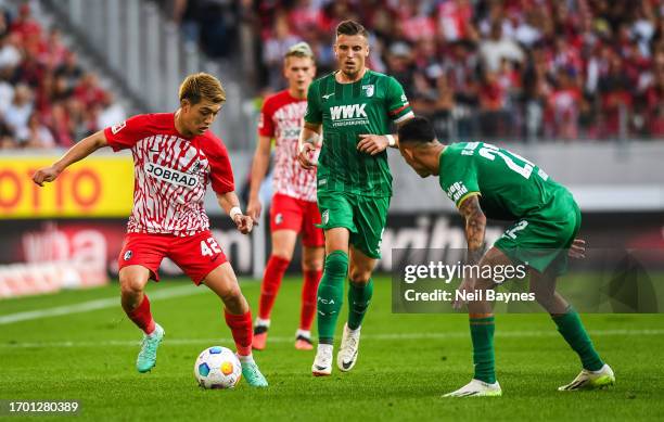 Ritsu Doan of SC Freiburg in action and Ermedin Demirovic of FC Augsburg looks on during the Bundesliga match between Sport-Club Freiburg and FC...