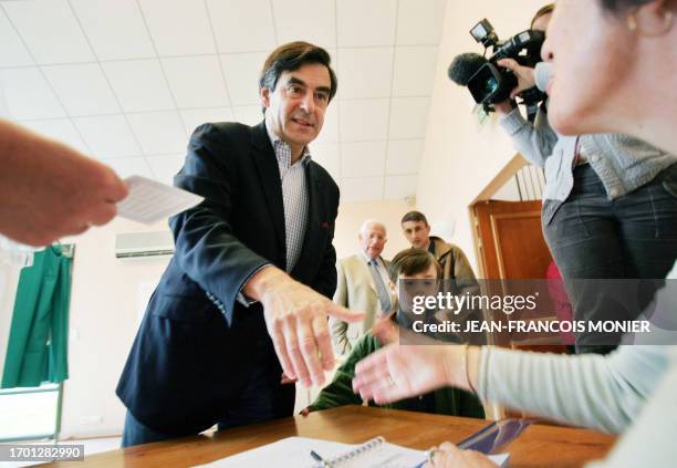Former French minister and political advisor to Nicolas Sarkozy, Francois Fillon, next to his son Arnaud, shakes hands of a polling official after...