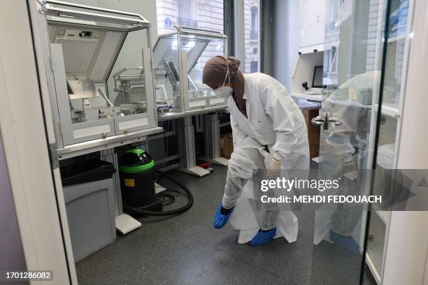 Rachida, a pharmacy technician, put on a protective suit before preparing medecines in the laboratory of the Delpech pharmacy in Paris, on September...