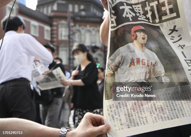 Copies of an extra edition of a newspaper are handed out in front of JR Tokyo Station on Oct. 2 reporting that the Los Angeles Angels' Shohei Ohtani...