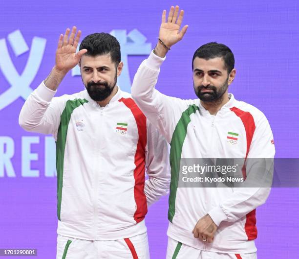 Iranian pair Noshad Alamiyan Daronkolaei and his brother Nima wave after finishing third in the men's table tennis doubles event at the Asian Games...