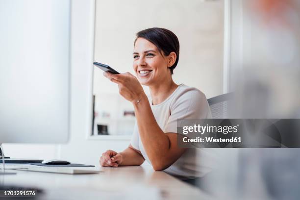 happy businesswoman sending voicemail on smart phone - speech recognition stockfoto's en -beelden