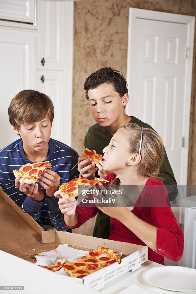 Three children eating pizza from take out box