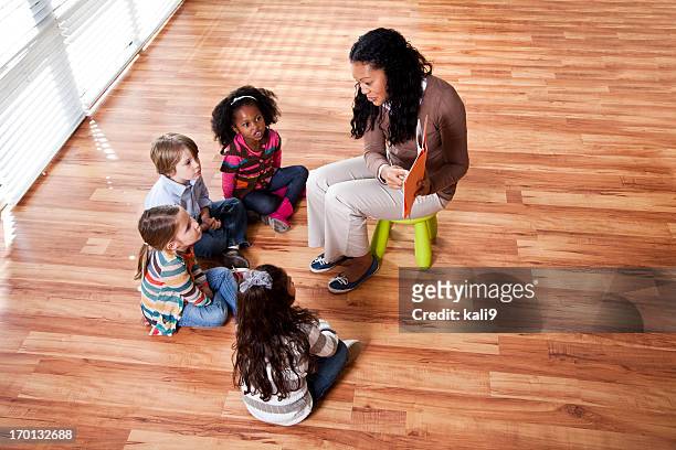 prescolare i bambini con l'insegnante di lettura in classe - bambini seduti in cerchio foto e immagini stock