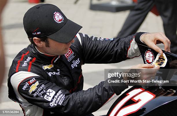 Will Power, in the Verizon Team Penske Chevrolet, applies a decal to his car, signifying his pole position start, after IndyCar qualifying for the...