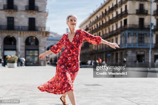 happy woman wearing red dress dancing on street in city - rotes kleid stock-fotos und bilder