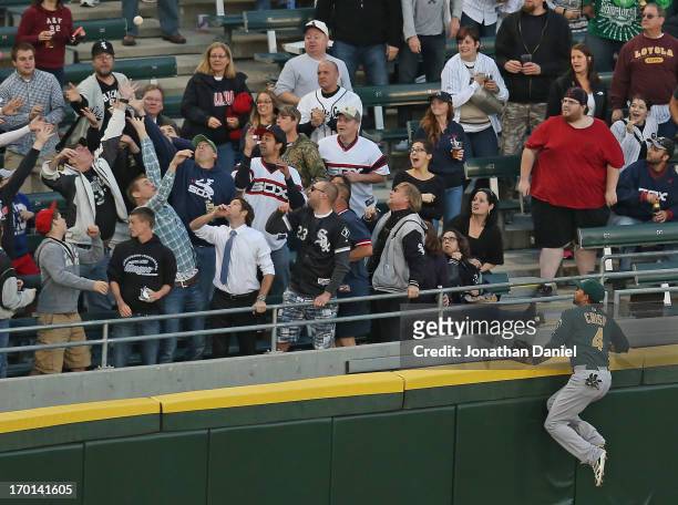 Coco Crisp of the Oakland Athletics climbs the wall and watches as fans try to catch a home run ball hit by Tyler Flowers of the Chicago White Sox at...
