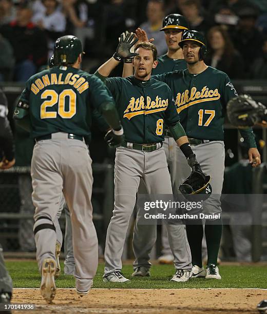 Josh Donaldson of the Oakland Athletics is greeted by Jed Lowrie, Adam Rosales and Nate Freiman after hitting a grand slam home run in the 6th inning...