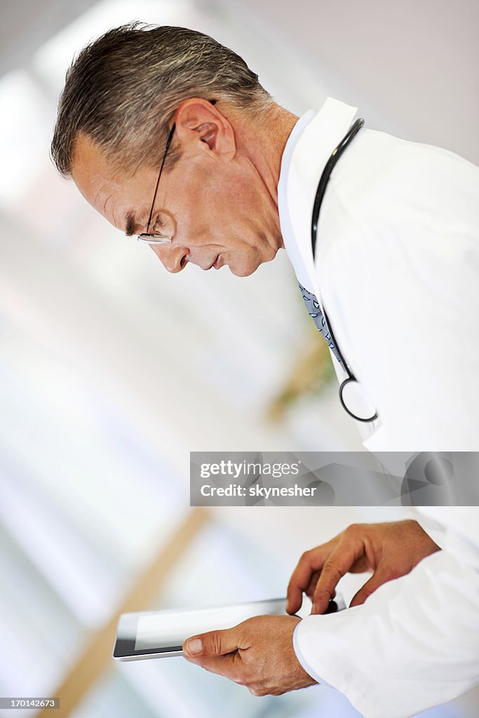 Serious doctor standing and using a digital tablet