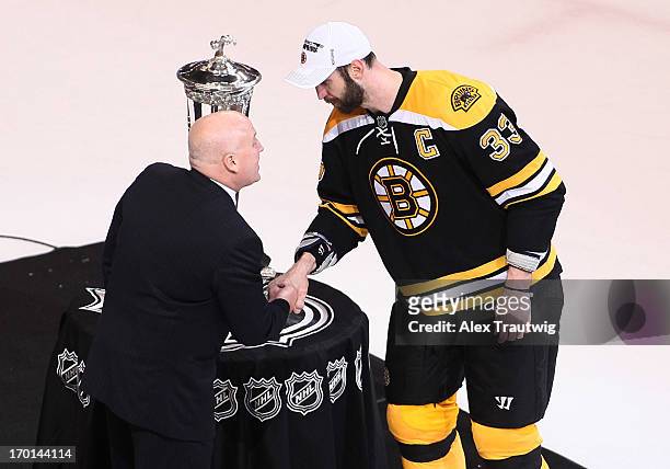 Deputy Commissioner Bill Daly shakes hands with Zdeno Chara of the Boston Bruins in front of the Prince of Wales Trophy after the Bruins defeated the...