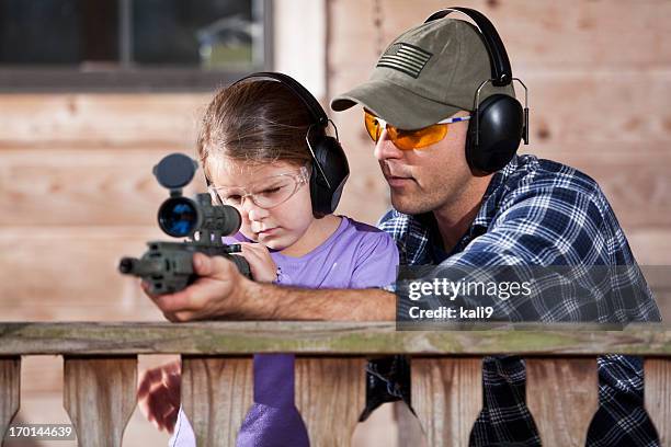 father teaching child to handle gun - schietsport stockfoto's en -beelden