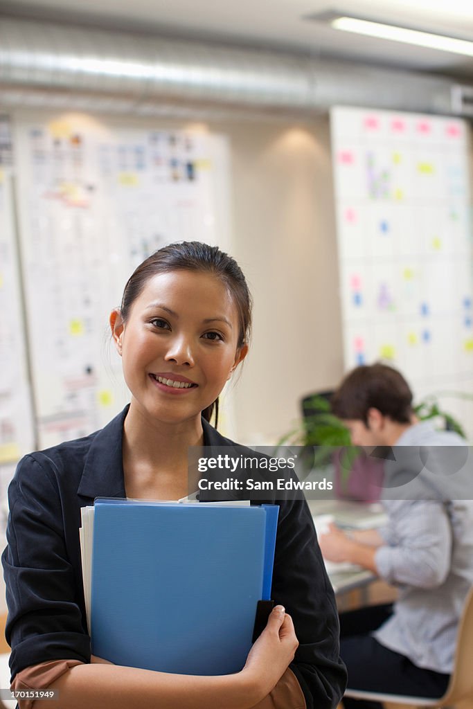 Portrait of smiling businesswoman with folders in office
