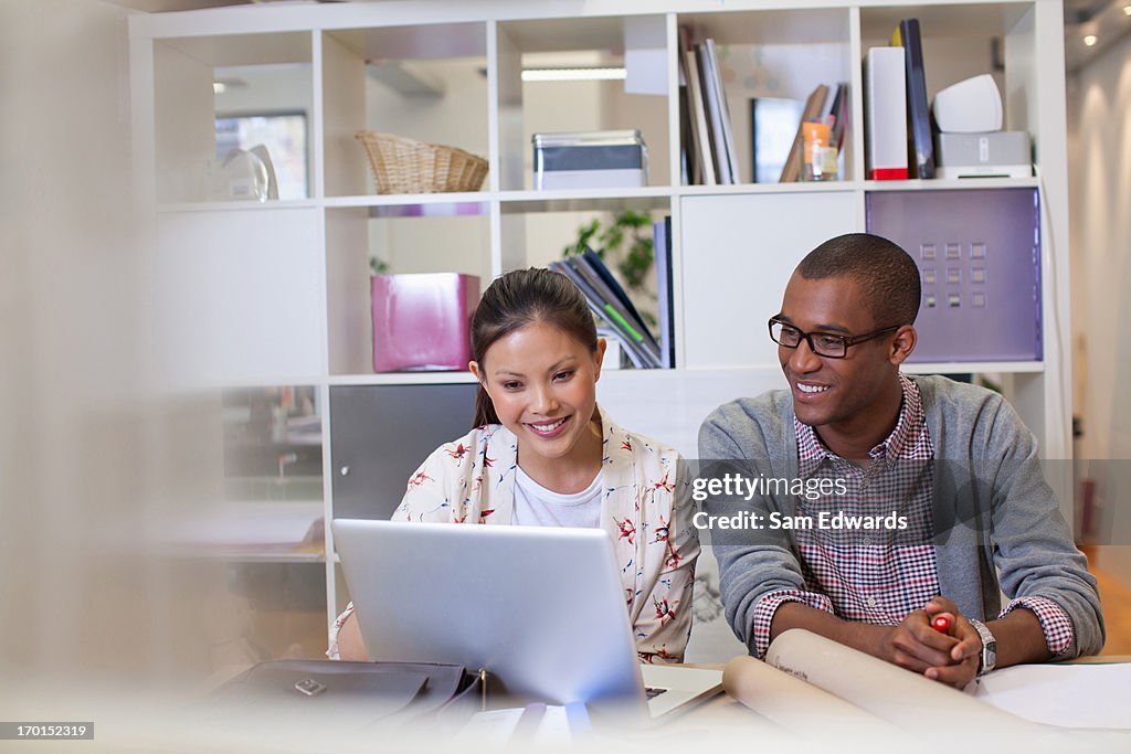 Businessman and businesswoman using laptop in office