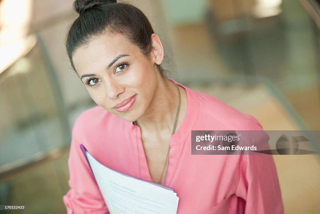 Porträt von lächelnd Geschäftsfrau mit Papierkram auf Treppe im Büro
