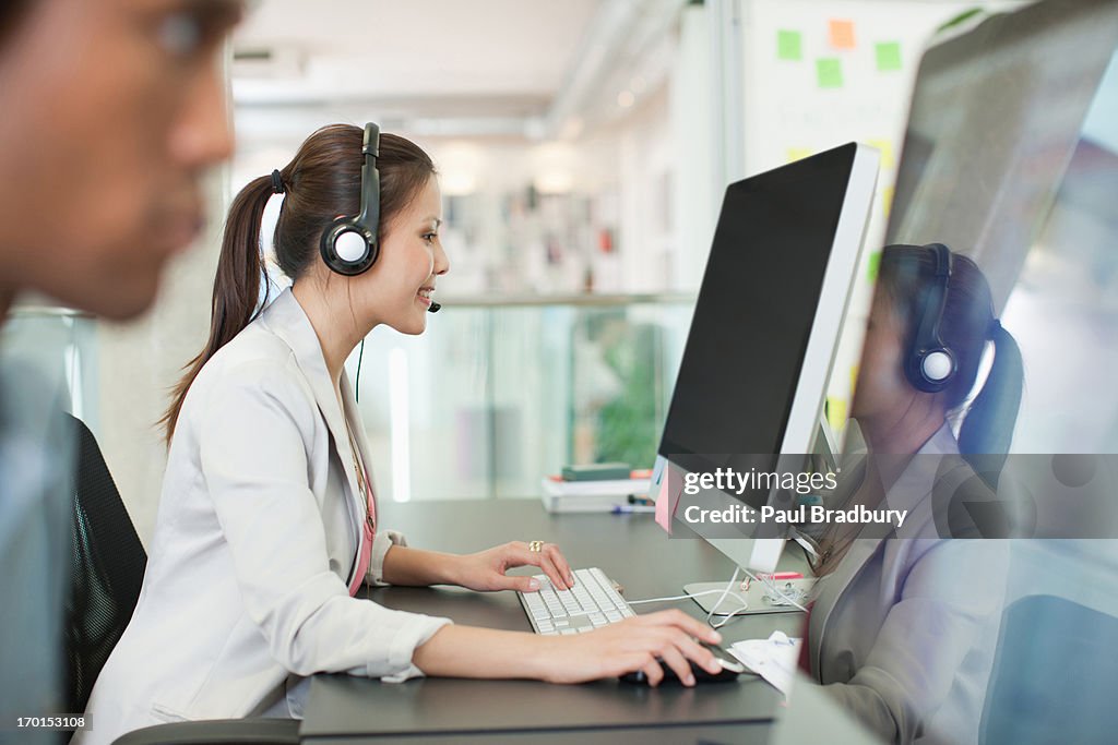 Ritratto di donna d'affari sicuri con le cuffie al computer in ufficio
