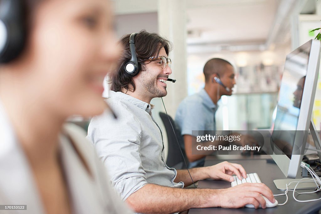 Business people with headsets working at computers in office