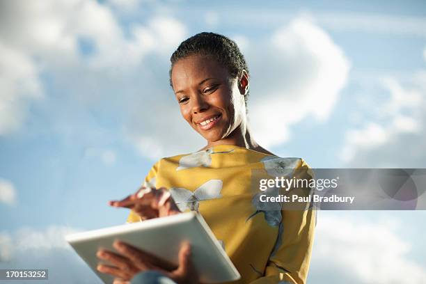 portrait of smiling businesswoman using digital tablet under blue sky with clouds - low angle portrait stock pictures, royalty-free photos & images